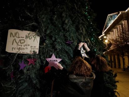 Dos mujeres colocan en un árbol de Navidad de la Plaza del Castillo en Pamplona dos estrellas, una de ellas con el nombre de Laura Luelmo y la otra con el numero de mujeres asesinadas este año.