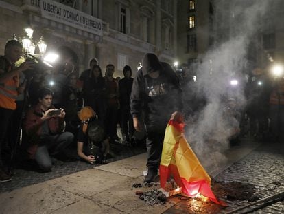 Un encapuchado quema una bandera española en la plaza de Sant Jaume de Barcelona.