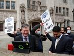 Uber drivers of the (ADCU), App Drivers & Couriers Union, celebrate as they listen to the court decision on a tablet computer outside the Supreme Court in London, Friday, Feb. 19, 2021.  The U.K. Supreme Court ruled Friday that Uber drivers should be classed as “workers” and not self employed.(AP Photo/Frank Augstein)