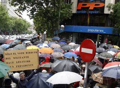 Uno de los asistentes a la concentración frente a la sede nacional del PP muestra una pancarta en la que pide que el líder del partido sea elegido directamente por los militantes.