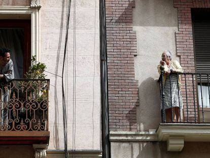 Dos vecinos conversan en el balcón de sus casas en Madrid este jueves durante la cuarta jornada laboral de aislamiento por el coronavirus. 