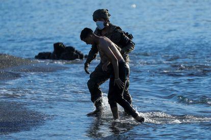 Un soldado asiste a un marroquí a su llegada a la playa del Tarajal. La Policía Nacional mantiene un equipo conjunto de Extranjería y Científica trabajando "las 24 horas" para acelerar los trámites administrativos previos a las repatriaciones.