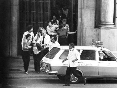 Primera salida de los rehenes del atraco al Banco Central, con una ambulancia del Ayuntamiento aparcada en la plaza de Cataluña de Barcelona.