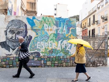 Dos personas pasan por delante de un grafiti en una calle de Lagunillas, en Málaga el 7 de marzo.