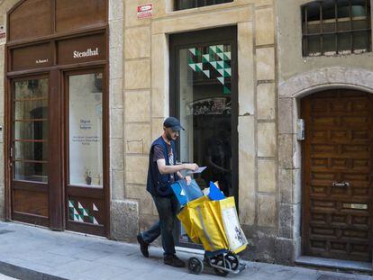 Un carter passa per davant d'un baix comercial en un carrer de Barcelona