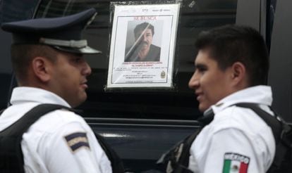 Dos policías ante el cartel de búsqueda de Guzmán.