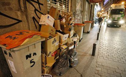 Un cami&oacute;n de recogida de basuras se acerca a unos contenedores llenos en una calle de Madrid