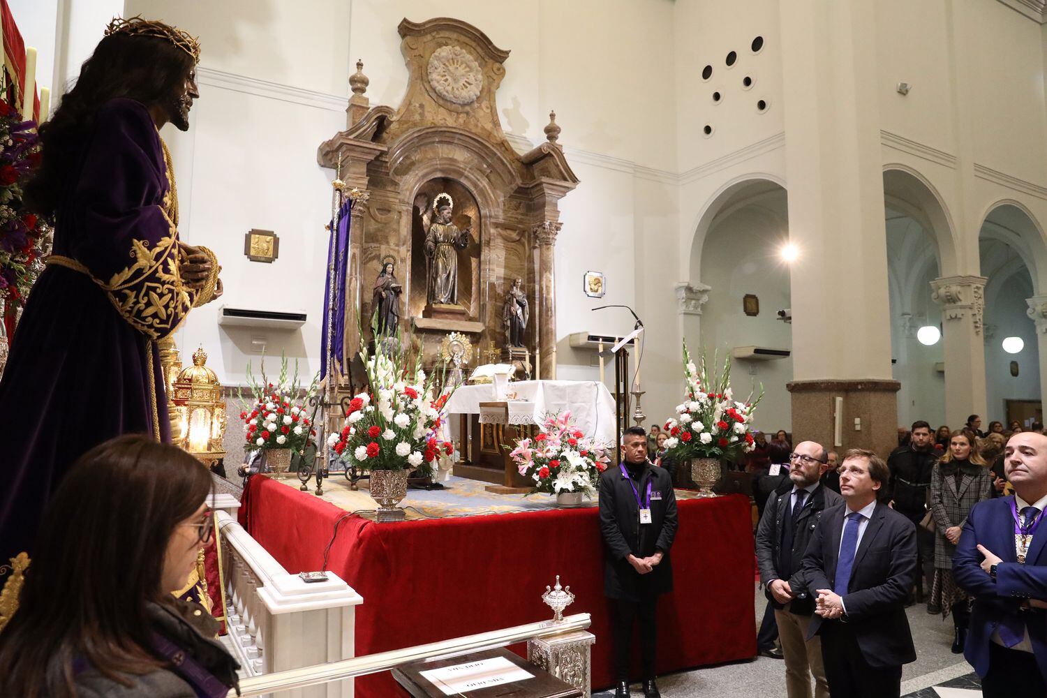 El alcalde de Madrid, José Luis Martínez-Almeida (centro), observa la imagen del Cristo el primer viernes de marzo en la Basílica de Jesús de Medinaceli con motivo de la tradición de venerarle y darle culto, en Madrid.