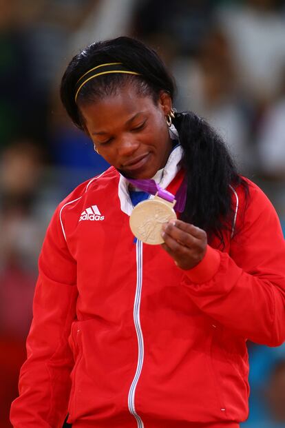 La judoka cubana Yanet Bermoy se retira el cabello (que se ha alisado) de la cara con una sencilla diadema negra y amarilla.