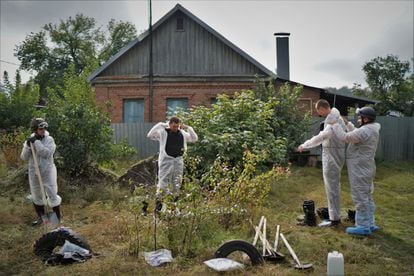 Un grupo de trabajadores se prepara antes de comenzar a desenterrar cuerpos este sábado en Izium