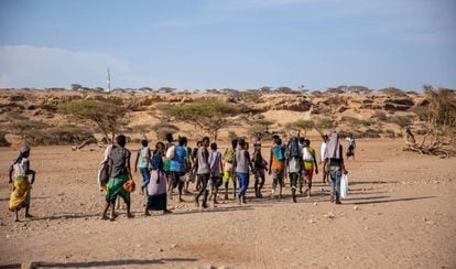 Migrantes etíopes en Obock, Djibouti, caminan hacia un área sombreada para esperar a que pasen contrabandistas y los lleven a Yemen en 2018.