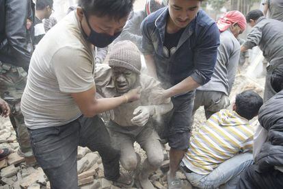 Dos voluntaris ajuden un home després de ser desenterrat d'entre la runa d'un edifici esfondrat pel sisme.