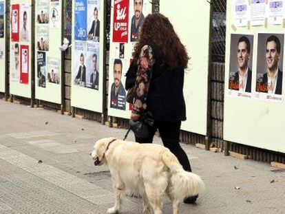Una mujer pasa por delante de carteles en Santurtzi (Bizkaia).