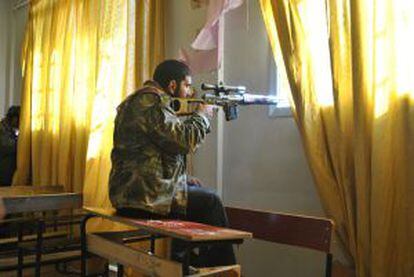 Un rebelde apunta con su rifle desde el pupitre de una escuela en la provincia de Homs.