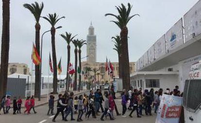 Un grupo de niños entra en la feria del libro. Al fondo la Mezquita Hassan II de Casablanca.