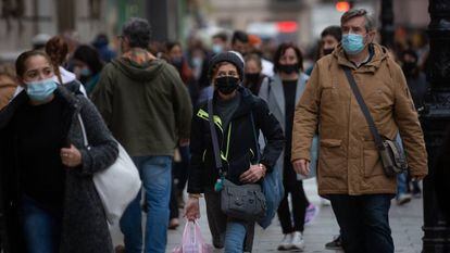 Viandantes caminan con bolsas por una vía de Barcelona.