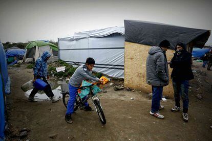 Uno de los pocos niños que hay en el campamento de Calais transporta un paquete en su bicicleta.
