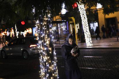 Una mujer camina cerca de un árbol decorado con luces navideñas en una calle del centro de Lisboa (Portugal), el 6 de diciembre de 2017.