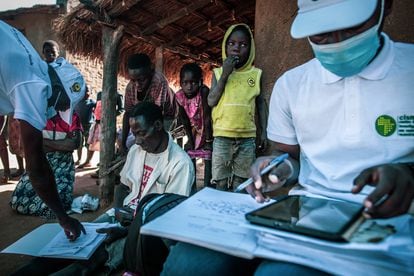 Rodeado por su mujer e hijos, Balança Manuel Sande rellena unos impresos que le han entregado los encuestadores del Centro de Investigación de Salud de Manhiça (CISM), que colaboran con el Proyecto Bohemia, un ensayo clínico que tiene como objetivo reducir la malaria utilizando ivermectina en el distrito mozambiqueño de Mopeia.