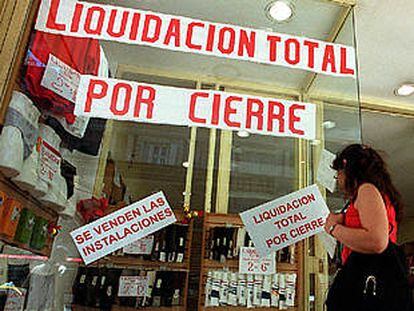 Una mujer observa el escaparate de un negocio de ropa en Buenos Aires que liquida existencias por cierre.