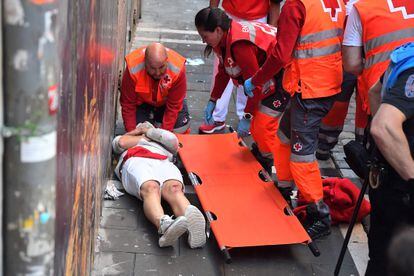 Un corredor es asistido por personal de la Cruz Roja. Seis personas han sido trasladadas a centros hospitalarios, dos de ellas por asta de toro, tras el tercer encierro de San Fermín.