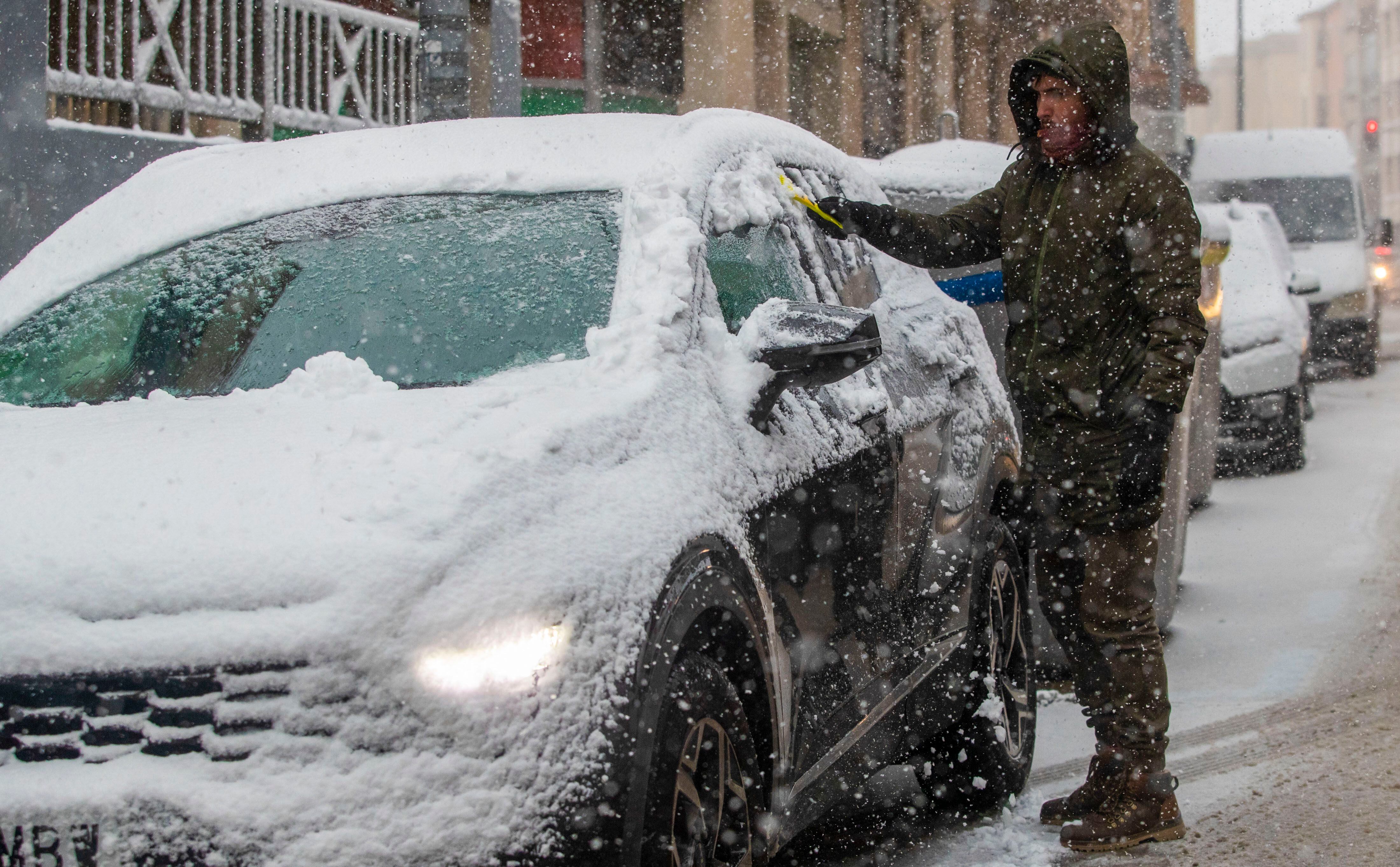 Un hombre retira la nieve de un vehículo en Soria capital.