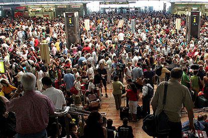 Miles de personas abarrotan las instalaciones del aeropuerto de El Prat de Barcelona a la espera de poder facturar el equipaje y emprender viaje.