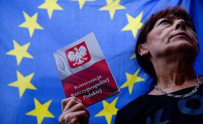Una mujer con la Constitución de Polonia, bajo una bandera de la UE.
