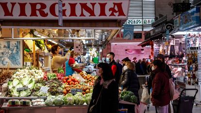 Varias personas compran en un puesto de fruta y verdura en el Mercado Central de Valencia.