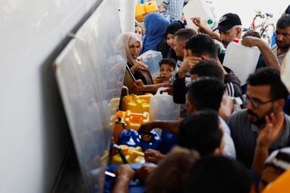 Palestinos se reúnen para recoger agua, en Khan Younis, en el sur de la Franja de Gaza, este jueves.