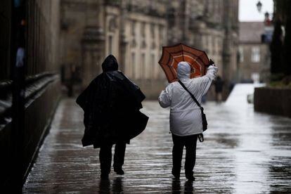 Una mujer arregla su paraguas afectado por la lluvia en Santiago de Compostela.