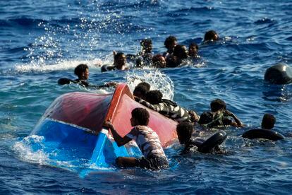 Migrants swim next to their overturned wooden boat during a rescue operation by Spanish NGO Open Arms at south of the Italian Lampedusa island at the Mediterranean sea, Thursday, Aug. 11, 2022. Forty migrants from Eritrea and Sudan, two children and one woman, were rescued by NGO Open Arms crew members and Italian coast guard after their boat overturned and started to sink. (AP Photo/Francisco Seco)