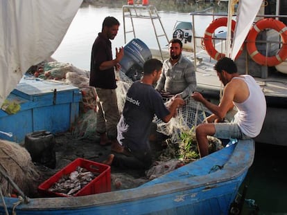 Cuatro pescadores recosen las redes antes de salir en alta mar en una de las barcas típicas de Katef, de tamaño medio.