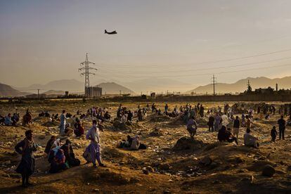 Un avión de transporte militar parte mientras decenas de afganos que quieren salir del país tras la llegada de los talibanes esperan en los alrededores del aeropuerto de Kabul en agosto de 2021.