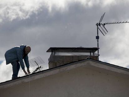 Un hombre cambia una antena antigua en una vivienda de Madrid.