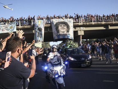 Cientos de aficionados saludan desde un paso elevado al coche fúnebre que lleva los restos de Diego Armando Maradona.