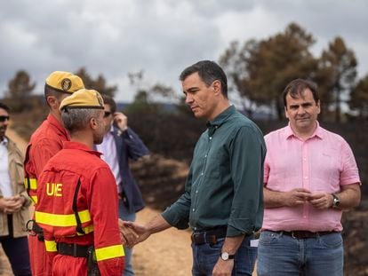 Pedro Sánchez, con el alcalde de Otero de Bodas, David Ferrero (derecha), saluda a dos efectivos de la Unidad Militar de Emergencias en su visita a la zona arrasada por el incendio en la sierra de la Culebra, en Zamora.