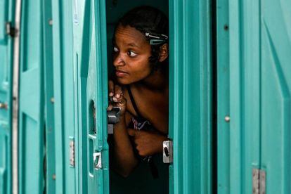 Una mujer mira por la puerta de la cabina de un baño portátil antes de tomar una ducha en un área acondicionada para personas sin hogar en el contexto de crisis por la covid-19, en Medellín, Colombia. 