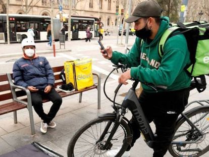 Repartidores de Glovo, Deliveroo y Uber Eats esperando un servicio en Barcelona, en una foto de archivo.
