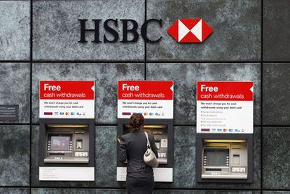 Una mujer extrae dinero de una cajero automático de una oficina de HSBC en Londres.