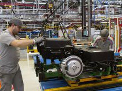 Dos operarios colocan las baterías de la furgoneta eléctrica Citroën Berlingo en la cadena de montaje de la planta de PSA.