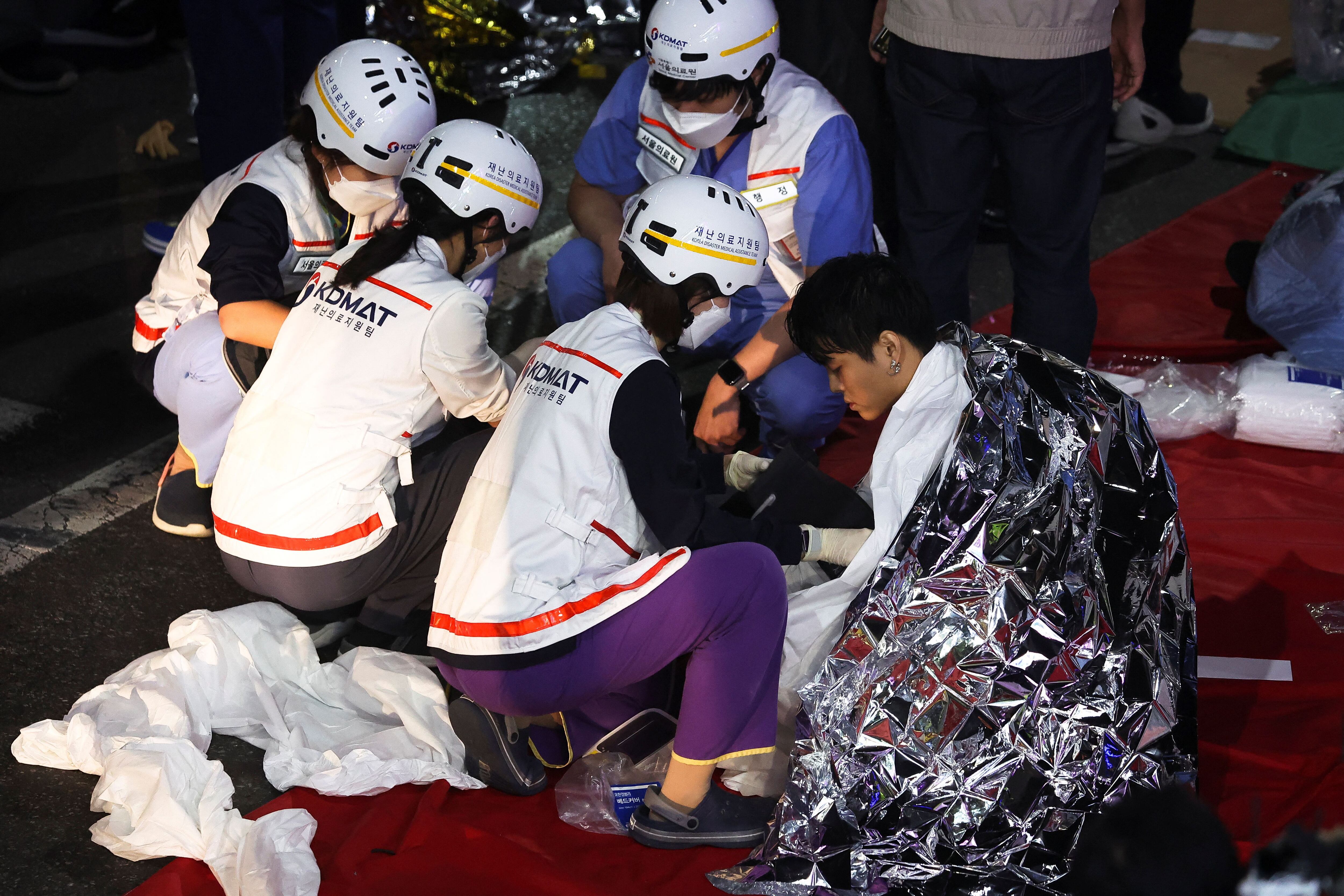 Un hombre recibe ayuda médica de miembros del equipo de rescate en el lugar donde decenas de personas resultaron heridas en una estampida durante un festival de Halloween en Seúl.