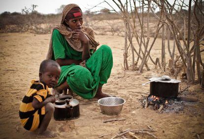 Una madre somalí cocina junto a su hijo en a las afueras de uno de los campos más nuevos.