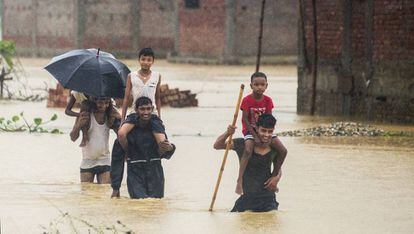 Varios nepalíes huyen de sus casas inundadas en Ramgadhwa, en Nepal, este domingo.