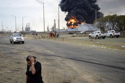 Una mujer pasa por delante de la refineria despu&eacute;s de la explosi&oacute;n.