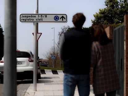 Un matrimonio que ha denunciado abusos sexuales sobre su hijo, ante el cartel que indica los juzgados de Majadahonda.