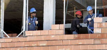 Tres obreros trabajan en la construcci&oacute;n de una vivienda. 