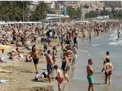Miles de turistas disfrutan de una soleada jornada en la playa del Postiguet de Alicante, durante el Domingo de Ramos.
