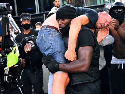 Patrick Hutchinson cargando a un hombre blanco agredido durante las manifestaciones y contramanifestaciones de Londres el pasado sábado. En vídeo, imágenes del rescate durante la manifestación y entrevista a Hutchinson.