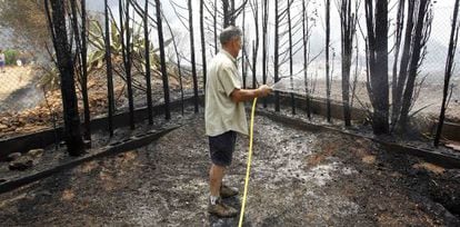 Un hombre riega su jardín en Monroi (Valencia).